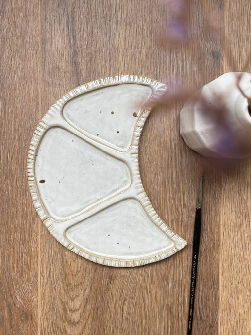 Ceramic dish on a wooden surface with a vase and brush